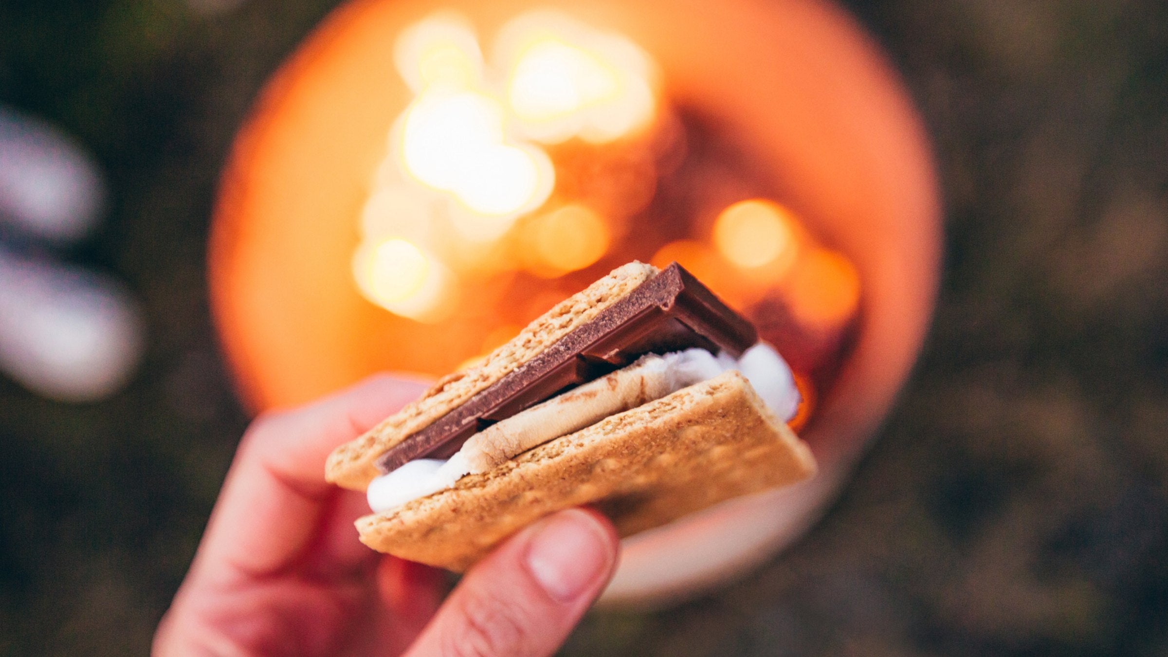 person holding a s'more over a campfire