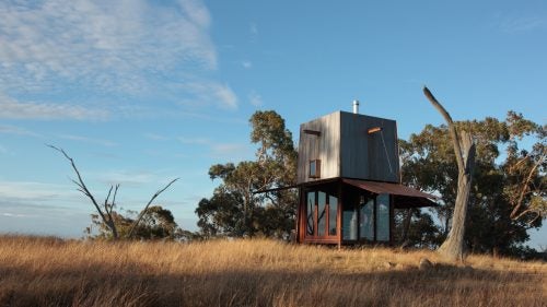 Located on a remote mountain, the tower features a mere 9 square-meter footprint and has panoramic surrounding views for hundreds of miles. When not in use, the awnings flip down to completely enclose the timber and glass interior and protect it from the elements. The building was constructed in Sydney, Australia, then transferred to its isolated home.