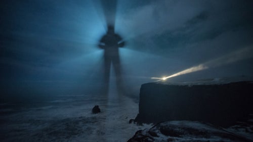 When I walked up to the edge (see next slide) of that cliff under the lighthouse, I noticed fog lingering about 100 yards offshore. I ran out to the arch (directly under me here), placed my Nitecore Tiny Monster torch behind me, and stepped into the light. Pictured: Dyrholaey.