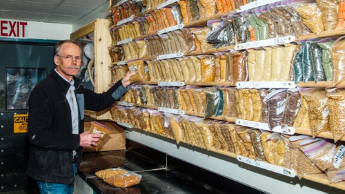 Rick Barrows shows a wall of different fish feeds manufactured at the USDA's Agricultural Research Service in Bozeman, Montana. Barrows has demonstrated that eight popular fish-farm species do as well or better on his fish-meal-free feeds, which helps the aquaculture industry reduce the pressure they’re putting on maxed-out forage fish stocks. The shelves hold 500 to 600 samples for approximately 20 different species. The USDA keeps the samples for about two years in case they need to go back and check them for nutrient content if fish show slow growth.