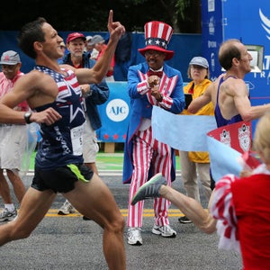 Scott Overall hits the tape, right,  to win the men’s open division while runner Ben Payne comes in second place at the finish line of the AJC Peachtree Road Race on July 4, 2015.