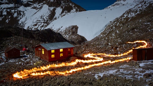 With petroleum as his paint, English photographer Simon Norfolk took to Africa’s second highest peak, Mount Kenya, to outline the mountains’ vanishing Lewis Glacier. Using old maps and meticulous GPS plotting, the fire lines represent an old section of the glacier, often a large distance from the glacier’s current front. Norfolk’s work, completed in 2014, is marked by grief but he hopes it also serves as a call to action. In his words, to think that “in ten or twelve years this magnificent glacier that has endured for millennia will exist only in photographs, is unbearable.”
Photo: Norfolk was born in 1963, the year of the glacier’s position depicted by this fire line. At that time only the small hut on the left existed. The larger structure with the lights on, called the Austrian Hut, was built in 1972 and served as Norfolk’s residence during this project in 2014.