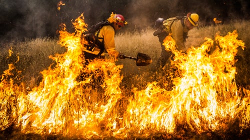 Firefighters dig a fire line around a spot fire on the Rocky Fire in Lake County, California, on July 30. As of August 12, the fire had consumed close to 70,000 acres and is one of 23 wildfires burning in California.