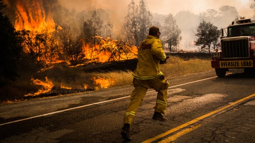 A firefighter runs to move a truck before it's overrun by a spot fire on the Rocky Fire in Lake County, California on July 30, 2015. As of August 5, the fire had consumed 69,600 acres and is one of 23 wildfires burning in California.