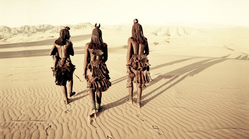 The Himba are an ancient tribe of an estimated 20,000 to 30,000 members located near the Kunene River in northwest Namibia and southwest Angola. They’re known for being tall, slender, and statuesque semi-nomadic herders. Most still live and dress according to ancient traditions and speak Herero—their language since the 16th century. The Himba live in scattered settlements of cone-shaped structures made of saplings bound together with palm leaves and plastered with mud and dung. If grazing is poor, the village will migrate to land with better opportunities, with young men leaving first to set up separate, temporary villages and move the cattle, while the women, children, and older men stay at the main settlement.