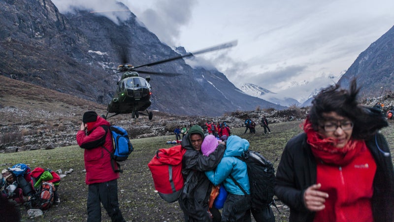 A group of survivors shield themselves against the powerful wind from a departing Nepalese Army helicopter. Monday, April 27, 2015.