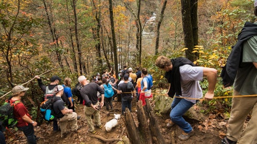 To reach the river in time for the high-noon start, spectators scramble two miles down a rain-sodden ravine. This year, a record 1,500 committed to the rainy hour-long hike in, hauling in dogs, chairs, and lots of blankets.