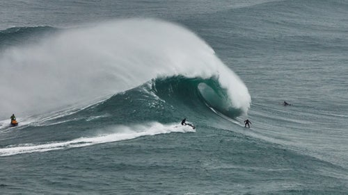 As Andrew Cotton catches a wave that he was towed into, Portuguese surfer João de Macedo goes without the support of a jet ski and paddles out to sea. It may be pride, or a desire for a new challenge, but in recent years, big-wave surfers at Nazaré have made it a point to paddle out to waves that, in the very recent past, were considered exclusively towable.