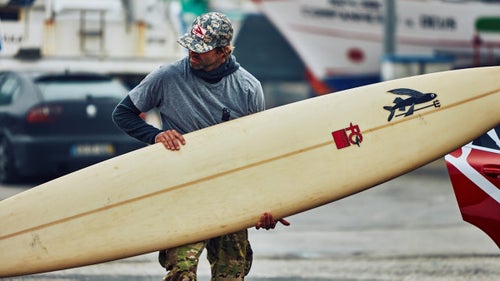 Kohl Christensen, of Hawaii, unloads one of his longer paddleboards. Each surfer brings a few boards out on the water every day, along with some food and water, which they store in the adjacent harbor south of the lighthouse.