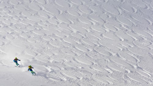 After a decade-long hiatus, Jackson Hole’s famous Powder 8’s competition returned last weekend. Pairs of skiers competed to create the most symmetrical figure eights while tearing down Cody Bowl just outside the ski area boundary. With one skier following the other, five judges also critiqued their timing and skiing style.
The event, which started in 1975, fell off back in the early 2000s as freeride and big mountain competitions gained popularity and synchronized skiing became passé. The resort decided to reinstate it as part of its 50th anniversary celebration, and, like many retro trends in skiing these days (think onesies, Pit Vipers) it was warmly welcomed back. Teams flew in from across the country to compete, GoPro ponied up $10,000 in prize money, and many hope there are plans to continue the competition next year.
Photo: Teresa Gurdin and Victor Gurdin ski their line during the competition.