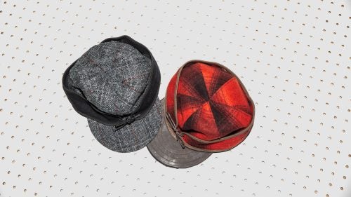 The classic Stormy Kromer cap (right), born from blustery Wisconsin winters, lets you slide the headband down over your ears when temperatures drop. This version has the classic red and black wool outer and a Horween leather brim. Also pictured: the Original Cap with Harris Tweed ($60).