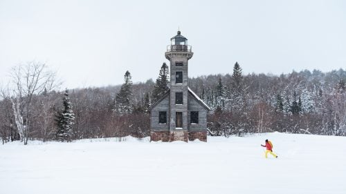 Pohl cross country skis past the East Channel Lighthouse on frozen Lake Superior en route to a shooting location.