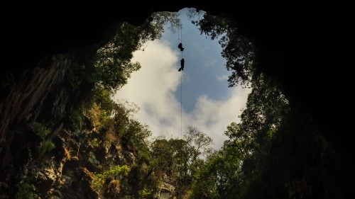American cavers were first to descend the 1,200-foot deep Sotano De Las Golondrinas, better known as the Cave of Swallows, in 1966. It’s one of the world’s largest cave shafts in the world and one of Mexico’s 13 natural wonders. The cave is so enticing that, in 2012, then President of Mexico, Felipe Calderon, was lowered by rope to the bottom of the shaft to experience it first-hand.
Today, there’s a paved road leading to the entrance of the cave to encourage tourism, and people from all over the world visit to peer over the edge and watch the white-collared swifts who call the cave home. Very few of these vistors actually rappel inside to see the bottom. Despite the popularity of this natural wonder, the inside of the cave is still a genuine wilderness experience. The limestone karst of the area of Acquismon is home to many caves, Sotano de Golondrinas being only one of them. Here is a collection of photographs from the Cave of Swallows and other shafts surrounding it.
Photo: Scott Christenson and Jerry Cindric ascend out of Sotano De Huasteca, a 420-foot deep limestone pit in Aquismon. Using mechanical ascenders to climb the rope, they are able to quickly and efficiently exit the cave. Rock climbing the walls in the cave would disrupt the nests and habitat of the white-collared swifts. Leaving behind climbing chalk and climbing bolts would be unnecessary to explore the cave and is damaging to the fragile ecosystem.