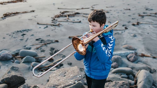 Simún Jacobsen playing trombone on the beach of Sandavágur on Vagar Island.
