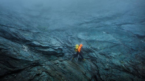 Kyle carefully picked his way across steep, wet granite slabs at the head of the Matukituki Valley.