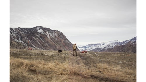 Alex approaches a gut pile as his dog, Shadow, follows. Fat, organs, and other animal parts commonly left behind by most hunters today remain valuable to Buffalo Bridge as food, clothes, and for crafting utilitarian objects. Horns can be used to make spoons and bones can be made into a variety of items including needles and knives.