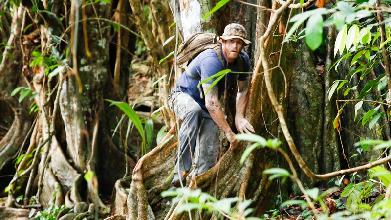 Tim Reames walking along the roots on the river bank.