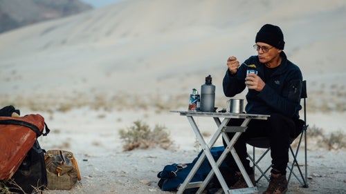Swaney eating breakfast below the Eureka Dunes. May 21, 2016.
I learned about Swaney from a good friend who’s been following him on Facebook, fascinated by stories and photos of huge rappels, remote natural bridges, slick rock dryfalls, and rattlesnakes. My friend and I have been exploring Death Valley regularly for 15 years, and we’ve had many hikes end abruptly at the foot of an impassible canyon dryfall.
I reached out to Swaney via Facebook, and he quickly replied within minutes with a thumbs-up emoji. Then: “You will have to join up. Been going every weekend this season. Lots of new canyons to check out.” One month later, I’m riding in his dust-coated Nissan Pathfinder, heading from Los Angeles to Death Valley, while he gives me lessons on rappelling.