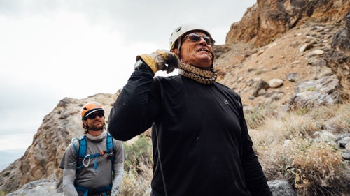Swaney plays with a snake in Sand Witch Canyon while Plummer looks on. I’ve visited Death Valley more than 30 times and had never seen a snake. Every day I spent with Swaney, he found at least one. May 21, 2016.
The weather is pleasant. We’re up around 5,000 feet, and it’s not too hot. We down-hike the drainage just a few hundred yards and reach our first rappel. Swaney and Plummer scope out potential anchor points. Gezik finds a little pool of standing water in a rock and scoops it into her bottle, using her bandanna as a filter. “Plenty of UV,” she says to explain its potability. There’s a desiccated, twisty tree growing near the edge of the rappel, and Swaney declares it perfect. He loops webbing around it, clearing a couple twigs out of the way, and then attaches a rapide quick link. Once the rope is thrown over the edge, he inspects its lie. The stone is sharp where it transitions to vertical. Swaney uses another rock as a hand sander to smooth the lip. “This could cut the rope,” he says. “Try not to pendulum or bounce.”