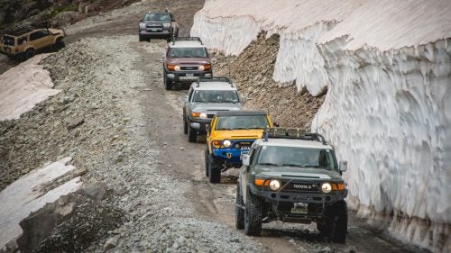 A line of FJ Cruisers and 4Runners make their way past mid-July snowbanks on the way up Imogene Pass.