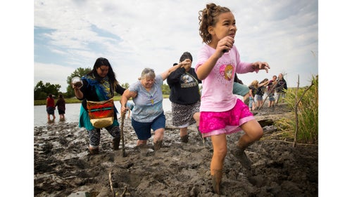 Isabella Flannery (9) of Kansas City, Missouri, picks her way through deep mud after praying with her mother, Stella, and other women on the banks of the Cannonball River near camp. Isabella and Stella came to North Dakota out of concern that if an accident occurs and the pipeline spills crude into the Missouri River, it will pollute not only Standing Rock’s water supply, but also their own and that of many others who live downstream.