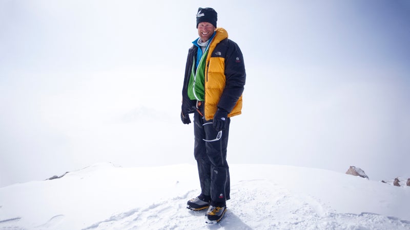 Climber Conrad Anker stands for a portrait on a snow mound with a white background.