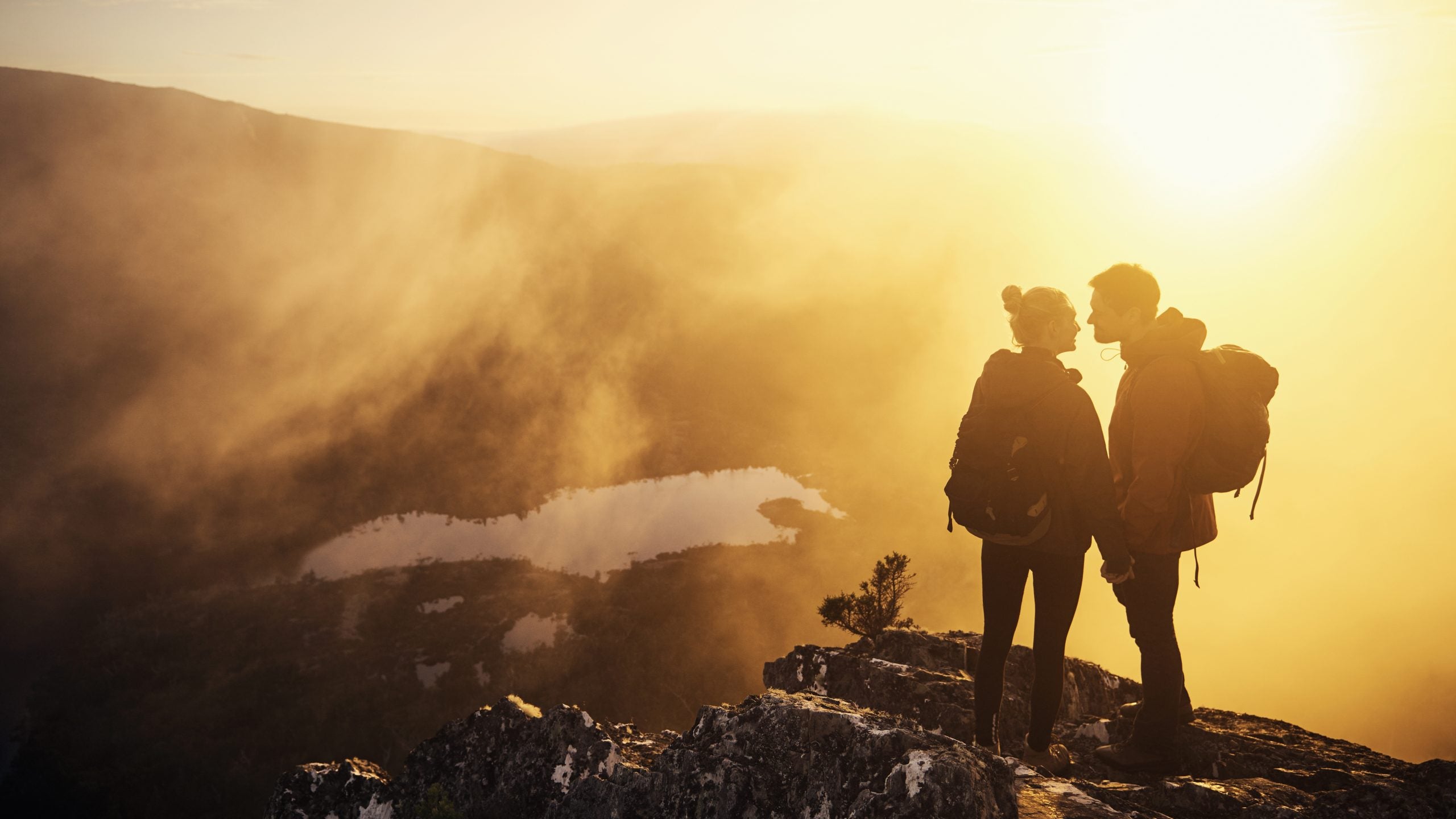 Shot of a young couple taking in the morning sun while hiking in the mountains
