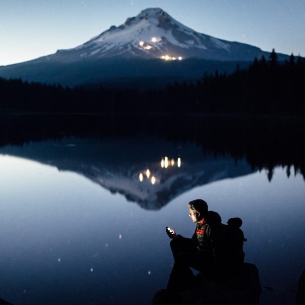Hiker plugs in on a lake shore in Oregon at twilight.