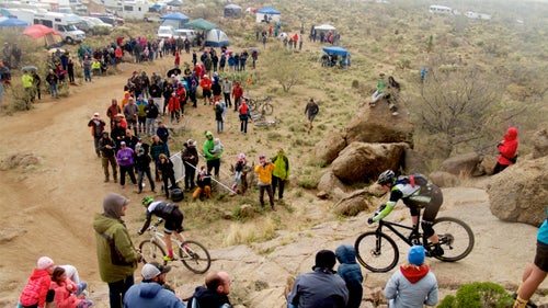 24 Hours in the Old Pueblo, one of the country’s great 24-hour races, went off this President’s Day weekend, complete with thundering rain, a rowdy party, and four former members of the U.S. Postal Service Pro Cycling Team. On a quiet patch of rock and dirt outside Tucson, Arizona, nearly 2,000 riders and even more spectators gathered on February 18 for a round-the-clock, relay-style mountain bike competition on a 16-mile loop through the desert.
Team WEDU24 caught attention for its star-studded roster—Lance Armstrong, George Hincapie, Christian Vande Velde, and Dylan Casey. But they didn’t come with major expectations of winning. Instead, like most other competitors, they were intrigued by the party and a chance to ride for 24 hours straight, and they found exactly what they were looking for. Photographer Maria Nasif followed the crew through a rainy night.
Photo: A crowd gathered at a popular spectator section called the Rock Drop just before the skies opened up and soaked the course.