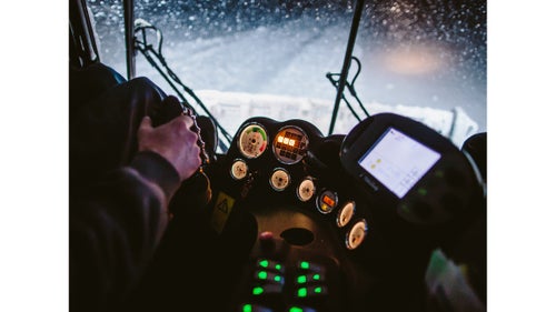 The cat’s cockpit has room for two, plus a sound system and heaters that blast hot air. Two levers on the left control the speed of each track, and a joystick on the right controls the plow and groomer blades. Most of the guys arrive with experience working construction rigs or tractors.