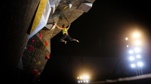 Emily Harrington dances between holds on the women's third route of the finals. Here, she swings over the wall's lip to reach the problem's top hold.