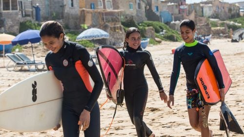 It might not have the name recognition of the North Shore or the Gold Coast, but Morocco’s Atlantic seaboard boasts some of the best surfing in the world. In recent years, it has launched a number of homegrown professional surfers onto the world stage. But never a woman. Now, for the first time in its seven-year history, there is a women’s division at the Agadir Open, a countrywide surf and bodyboard competition held on on a stretch of shoreline home to Morocco’s premier breaks. The event is run by the Imourane Surf Association, a local nonprofit that counts pro Moroccan riders Ramzi Boukhiam, who is sponsored by Quiksilver, and Othmane Choufani among its members. This year, ten women took to the waves during the three-day contest, which started on March 24. Meryem El Gardoum, a 20-year-old native of Tamraght, won the surf division, outscoring four competitors in her 13-to-38 age group with a combination of wave choice, maneuvers, and style.
These women are not alone. A swell of female Muslim surfers have made headlines in recent years, from Gaza to Iran to Bangladesh. But with seven women’s competitions per year, national championships, and female members on the national team, the surfeuses from Morocco are raising the bar. Photographer Mary Mathis and reporter David Fuchs, who produced this story with Round Earth Media, were on the ground to capture several women who competed at the Agadir Open last weekend.
Photo, from left: Surfers Lilias Tebbai, 12, Kenza Guemmi, 11, and bodyboarder Ines Tebbai, 10, exit the water at Devils Rock, Tamraght.