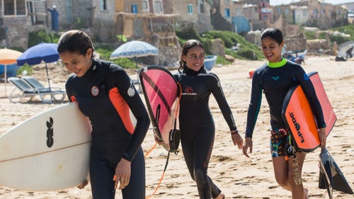It might not have the name recognition of the North Shore or the Gold Coast, but Morocco’s Atlantic seaboard boasts some of the best surfing in the world. In recent years, it has launched a number of homegrown professional surfers onto the world stage. But never a woman. Now, for the first time in its seven-year history, there is a women’s division at the Agadir Open, a countrywide surf and bodyboard competition held on on a stretch of shoreline home to Morocco’s premier breaks. The event is run by the Imourane Surf Association, a local nonprofit that counts pro Moroccan riders Ramzi Boukhiam, who is sponsored by Quiksilver, and Othmane Choufani among its members. This year, ten women took to the waves during the three-day contest, which started on March 24. Meryem El Gardoum, a 20-year-old native of Tamraght, won the surf division, outscoring four competitors in her 13-to-38 age group with a combination of wave choice, maneuvers, and style.
These women are not alone. A swell of female Muslim surfers have made headlines in recent years, from Gaza to Iran to Bangladesh. But with seven women’s competitions per year, national championships, and female members on the national team, the surfeuses from Morocco are raising the bar. Photographer Mary Mathis and reporter David Fuchs, who produced this story with Round Earth Media, were on the ground to capture several women who competed at the Agadir Open last weekend.
Photo, from left: Surfers Lilias Tebbai, 12, Kenza Guemmi, 11, and bodyboarder Ines Tebbai, 10, exit the water at Devils Rock, Tamraght.