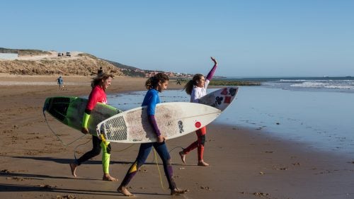 “I’ve been competing for years, and now this is the first time my daughters have competed with me,” says Berrada, who picked up surfing while pregnant with her second daughter, Kenza Guemmi. “Since I had my daughters, I’ve dreamed of them competing with me. I hope they’re going to continue and that this will motivate them.”
Above, from left: Berrada, Lilias Tebbai, and Berrada’s older daughter, Ghita Gemnmi, 16, head out to compete in the semifinals.