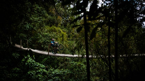 Guatemala isn’t known for its mountain biking. And that’s a good thing. This yet-to-be-overrun spot is littered with great riding on everything from mountainous Mayan footpaths to carefully placed flow trails that run through lush jungles. Last month, photographer Max Whittaker followed Diamondback rider Eric Porter and a couple of guests as they sampled the goods.
PHOTO: Eric Porter wheelies across a suspension bridge during a 12-mile flow-trail descent through dense cloud forest at the private El Zur Mountain Bike Park outside the city of Antigua. The trail took more than four years to build.