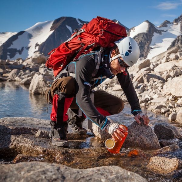 Kaare Iverson fills his water bottle from a glacial stream en route to a climbing route in Bugaboos Provincial Park, British Columbia