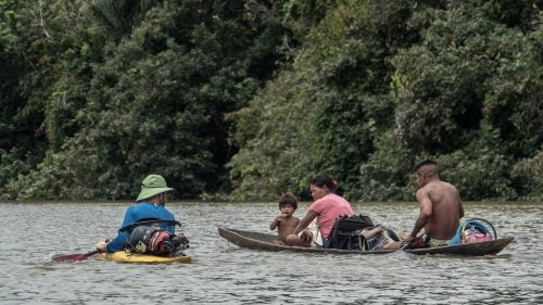 On April 18, Jules Domine (left) speaks with a family just up river from the village of Lerida about three weeks into the trip. Shortly after this photo was taken, Domine, Serrasolses, and Korbulic paddled ahead, and were stopped by an armed group in a wooden canoe with an outboard motor. Stookesberry and Rice were informed of the situation by villagers on the shore, so they paddled to the opposite side of the quarter-mile-wide river to avoid an encounter themselves. It didn’t work. The armed group—which identified itself as a dissident FARC movement—found the remaining kayakers after a short search. But after searching and questioning each kayaker, the FARC rebels granted them passage into the village where they were free to spend the night.