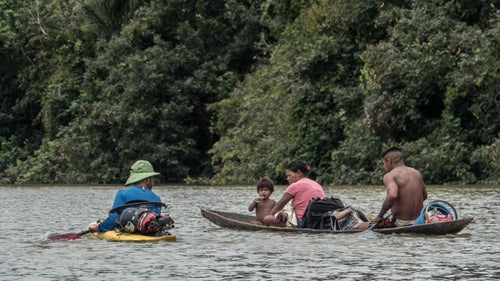 On April 18, Jules Domine (left) speaks with a family just up river from the village of Lerida about three weeks into the trip. Shortly after this photo was taken, Domine, Serrasolses, and Korbulic paddled ahead, and were stopped by an armed group in a wooden canoe with an outboard motor. Stookesberry and Rice were informed of the situation by villagers on the shore, so they paddled to the opposite side of the quarter-mile-wide river to avoid an encounter themselves. It didn’t work. The armed group—which identified itself as a dissident FARC movement—found the remaining kayakers after a short search. But after searching and questioning each kayaker, the FARC rebels granted them passage into the village where they were free to spend the night.