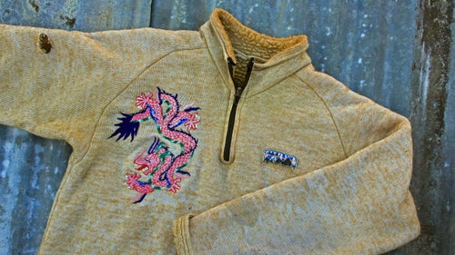 Original Patagonia Pile
In 1976, Malinda Chouinard lucked into bolts of the hard-to-find fabric in the California Merchandise Mart, marketed as toilet seat covers. The jacket was donated by one of Chouinard’s whitewater paddling pals and fellow Do-Boy John Wasson, the husband of Patagonia label designer Jocelyn Slack. Wasson tells the story of how his jacket acquired its dragon “tattoo”:
“In the spring of 1979, I was one of three kayakers on an American Sportsman trip in Nepal,” writes Wasson. “Two films would show a group of climbers making the second ascent of Ama Dablam, and then kayakers running the Arun River in western Nepal. The kayakers were invited to come to base camp and perhaps carry some loads higher up on the mountain. The day before we flew to Lukla, I got a guy in a small, dark shop in Kathmandu to put the dragon onto my pile. He literally ‘painted’ it freehand with an embroidery machine, changing thread colors in seconds.
“I chugged my way up and down the mountain mostly alone. The tricky parts all had fixed ropes. There was talk of a second summit team, but at the end there were only Doug Robinson and me interested in going higher. We met up at the highest camp and had an almost perfect summit day followed by a slow, headlamp-lit descent back to the tent. Naturally the Dragon Pile was along for the ride. Paddling the Arun was also great, but that’s another story.”