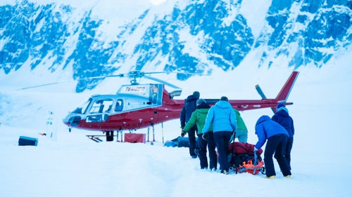On June 5, Bono left 14 camp to head back down to basecamp in preparation for an attempt at the speed record. On the way out, Bono’s friend, Metzler, began complaining of stomach pain. “Where?” she asked. “Lower right,” Metzler responded. Bono immediately suspected that Metzler was suffering appendicitis. By the time they got near basecamp, Metzler was in bad shape, and they were forced to load him onto a gear sled and pull him to camp. Later, as seen in this photo, they loaded Metzler onto a helicopter that flew him to the hospital in Anchorage where he underwent successful surgery for appendicitis.