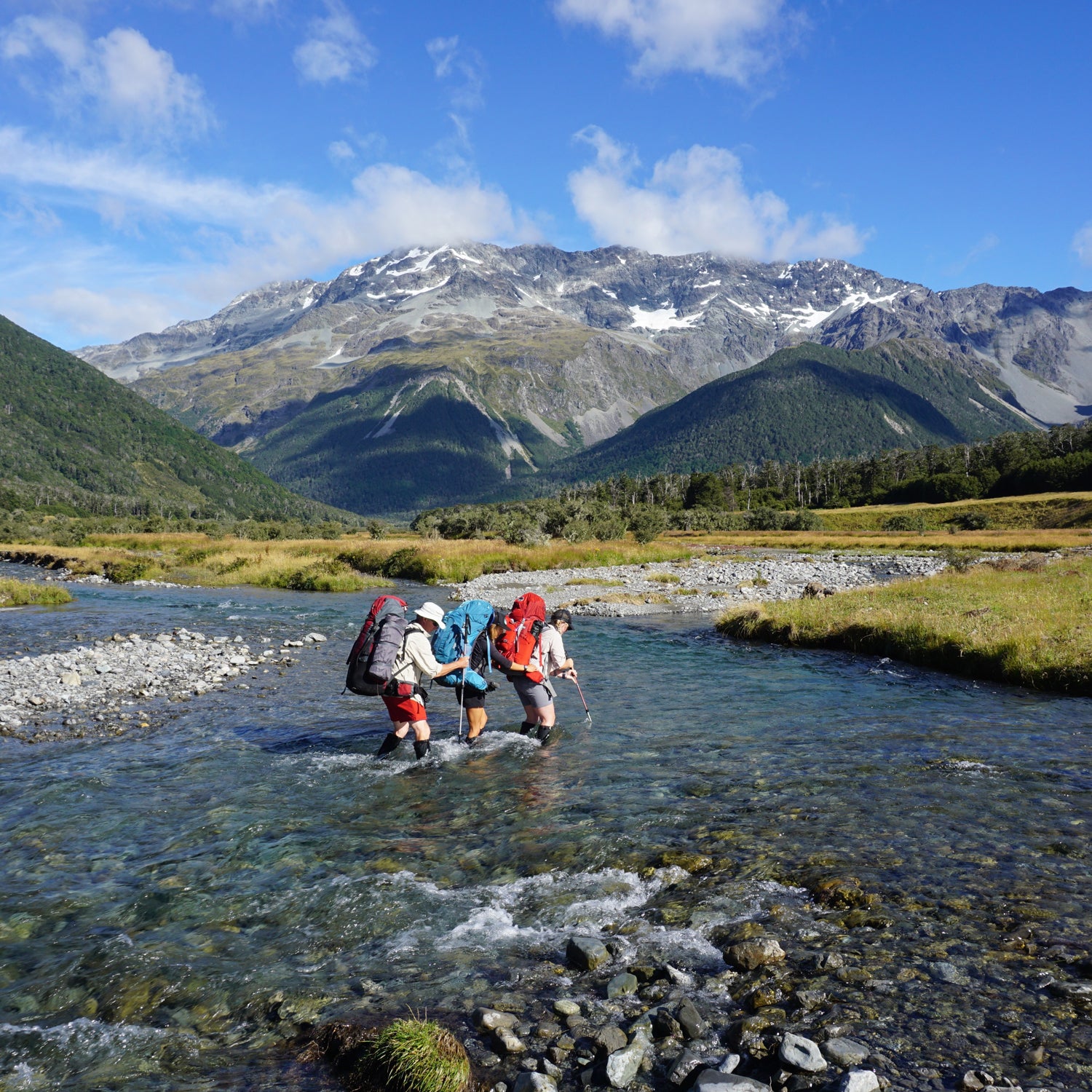 Hiking partners cross a stream near Nelson Lakes, New Zealand.