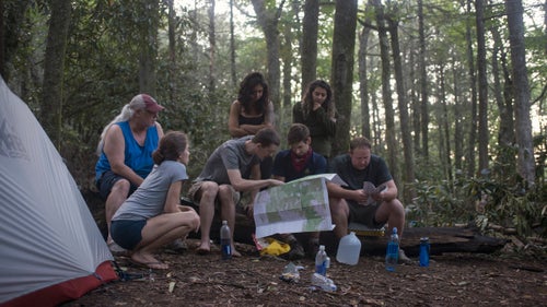 THE APPALACHIAN TRAIL, NEAR FRANKLIN, NORTH CAROLINA – 08/21/2017: At camp hikers discuss potential eclipse viewing points along the Appalachian Trail. Simon Farr (middle, wearing a red bandana), from Asheville, North Carolina, shows old maps of the area to section hikers at Carter Gap, five miles south of the centerline of eclipse totality. As local families and tourists pour into the area, die-hard hikers plan for quieter, and harder to reach areas to witness the eclipse. Farr works on trail maintenance in the Southern Appalachians, and is hiking towards his own secret hiking area. “I’ve got a good place planned,” he said ”it’s nice and peaceful, and tucked away under a small cliff edge - no one’ll find it.” CREDIT: Spike Johnson for Outside Magazine.