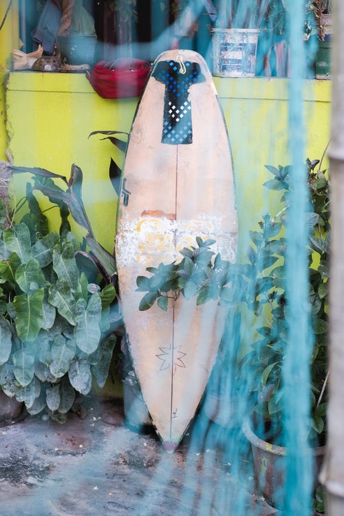 An old buckled surfboard that has been stitched back together with resin and fiberglass sits in a patio behind a fishing net in the aptly named Fisherman Colony neighborhood of Mahabalipuram. While boards in the past had been more scarce, nowadays many foreigners visiting town often leave their surfboards behind, and local surfboard shapers have started to make their own boards. Many of the locals also frequently take the 4hr flight to Bali, Indonesia where they stock up on boards and return to keep the supplies healthy in Mahabs.