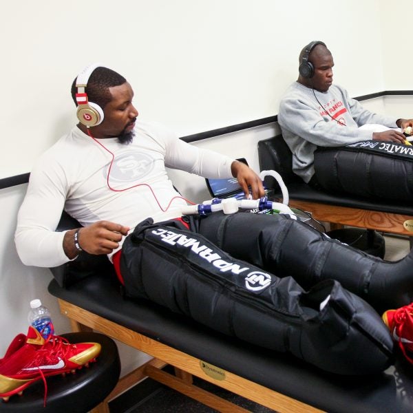 NaVorro Bowman and Frank Gore of the San Francisco 49ers refresh their legs with a Normatec treatment in the locker room prior to Super Bowl XLVII February 2013.