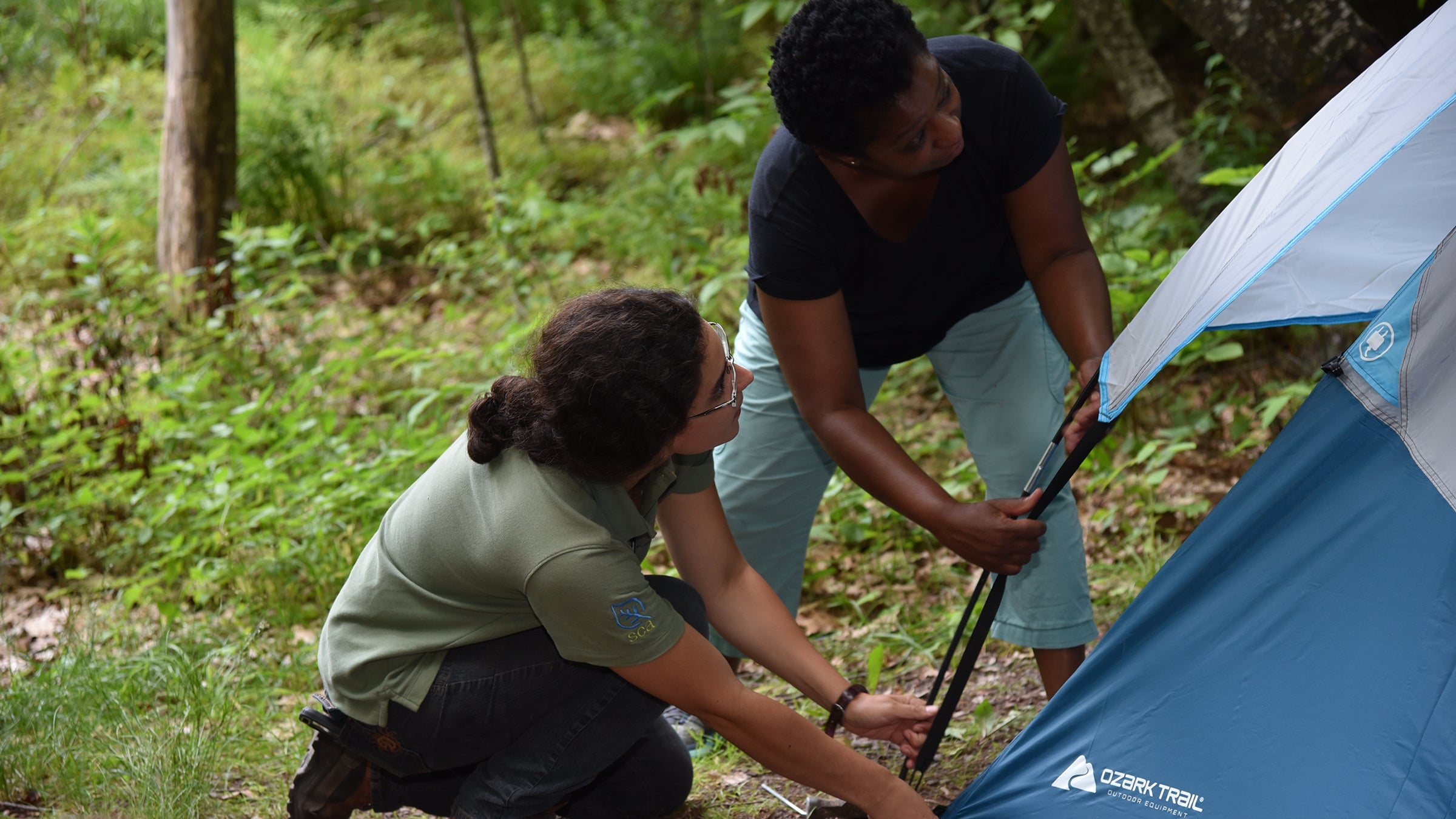 A camp ambassador shows a first-timer how to set up a tent. 