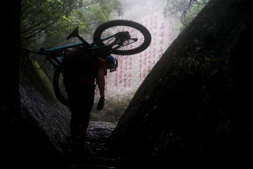 A wall of propaganda slogans looms out of the mist as Max Schumann carries his bike up a steep trail on Mount Myohyang. While we expected to be greeted by political propaganda among Pyongyang’s city streets, such propaganda, hand-chiselled in rock faces, came as a surprise as we explored the forest trails of Mount Myohyang.