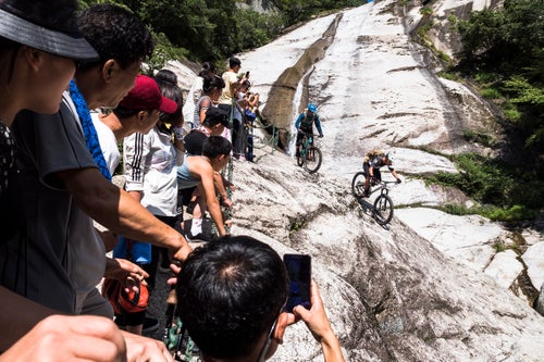Spectated by a line of North Korean day-hikers, Schumann and Philipp descend a bedrock outcrop on Mount Myohyang. The novelty of seeing mountain bikers sharing their trails drove most North Korean hikers to reach for their North Korean branded smartphones to snap photos or video of the us. While such images and video could then be shared on North Korea’s own intranet, North Korean citizens have no connection to the World Wide Web.