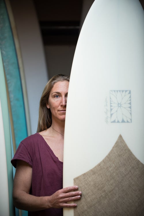 Ashley Lloyd Thompson stands with one of her finished boards. Growing up on California waves, Ashley wanted to balance her respect for traditional longboard surfing and her commitment to a healthy environment. All Ashley Lloyd Thompson Surfboards are ECOboards—they’re all Green Certified by the Sustainable Surf Organization—using less toxic materials and bio-based epoxy resins.