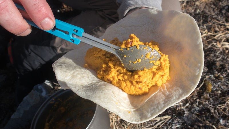 After the egg mixture is scrambled, transfer it into a tortilla.