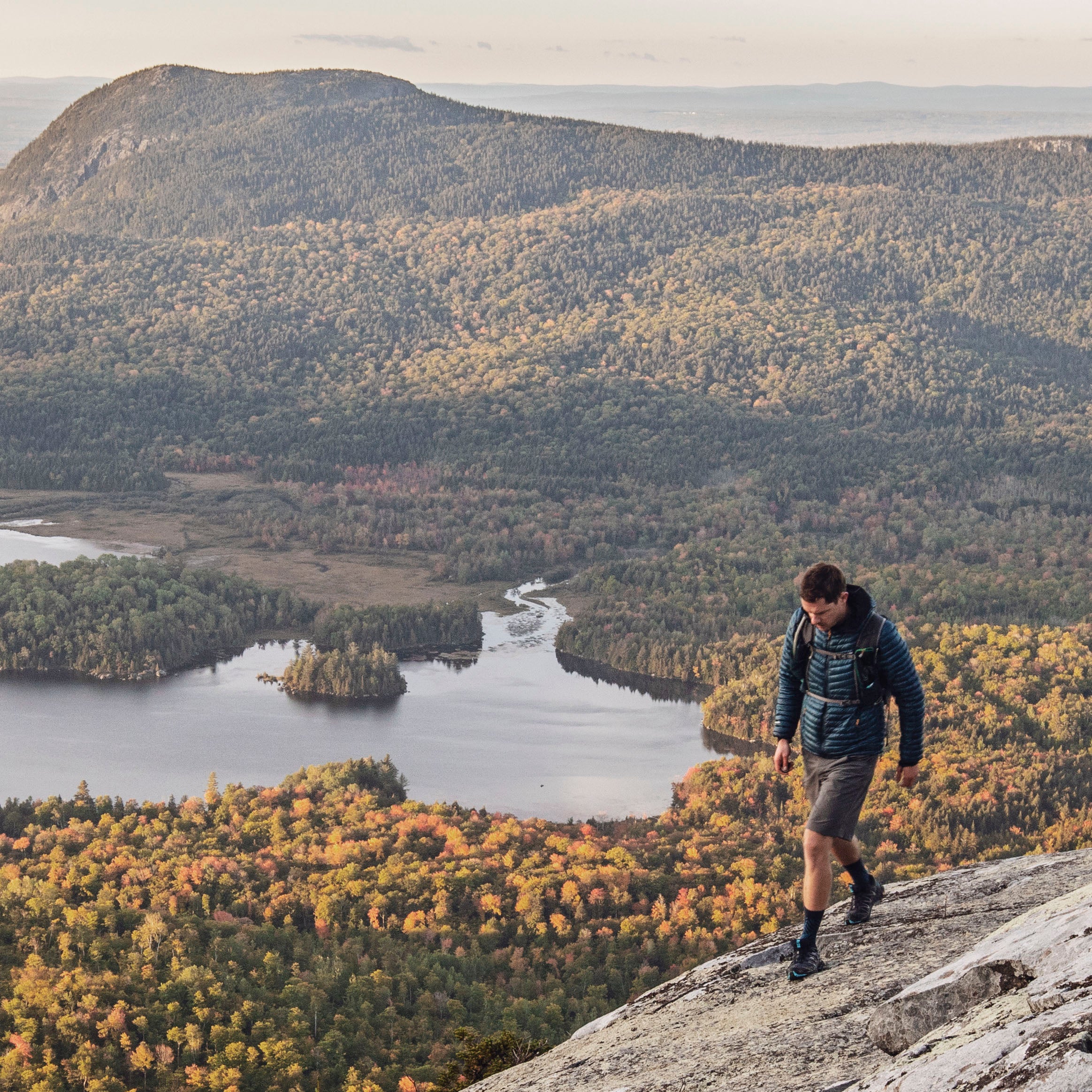 male hiker walks along cliff with view on Appalachian Trail, Maine